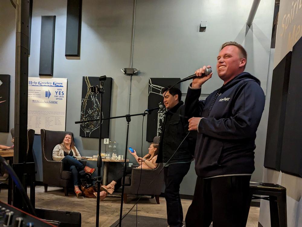 a singer performing into a microphone at a venue while guests look on