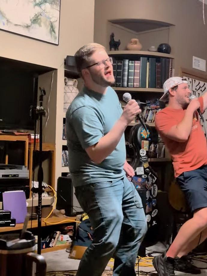 the host singing with a guest at a house-party karaoke night