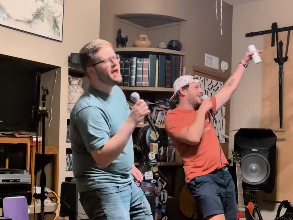 two singers performing with a speaker and guitar set up for a house party